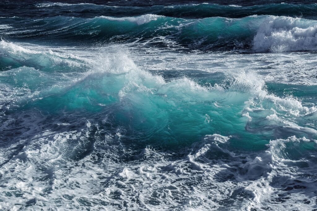 Photo de vagues tumultueuses en mer avec des eaux turquoise et blanches écumantes, capturant la puissance et la beauté de l'océan sous une lumière naturelle, sans éléments humains ni objets visibles.