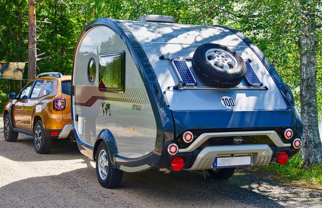 Cette image illustre un voyage en camping-car au Maroc avec une caravane moderne attelée à un SUV orange
