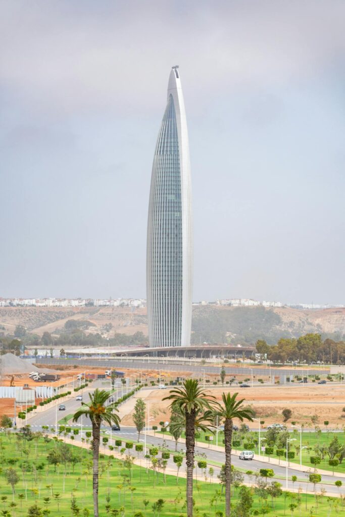 L'image met en lumière l'harmonie entre Traditions et Modernité au Maroc en présentant la Tour Mohammed VI, un gratte-ciel élancé et futuriste qui domine le paysage. La conception architecturale audacieuse de la tour symbolise la modernité et l'ambition du pays.