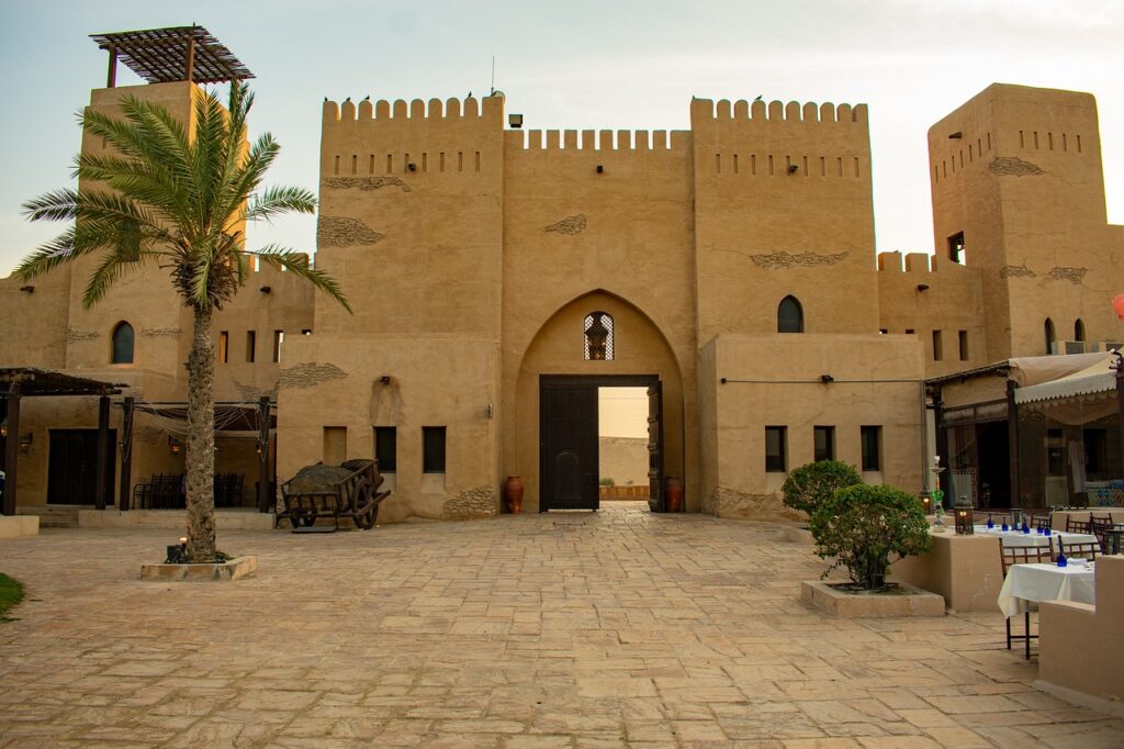 Cette image présente une vue pittoresque d'une structure emblématique à Taroudant, au Maroc. Elle met en scène une imposante porte fortifiée en pisé, typique des remparts historiques de la ville,