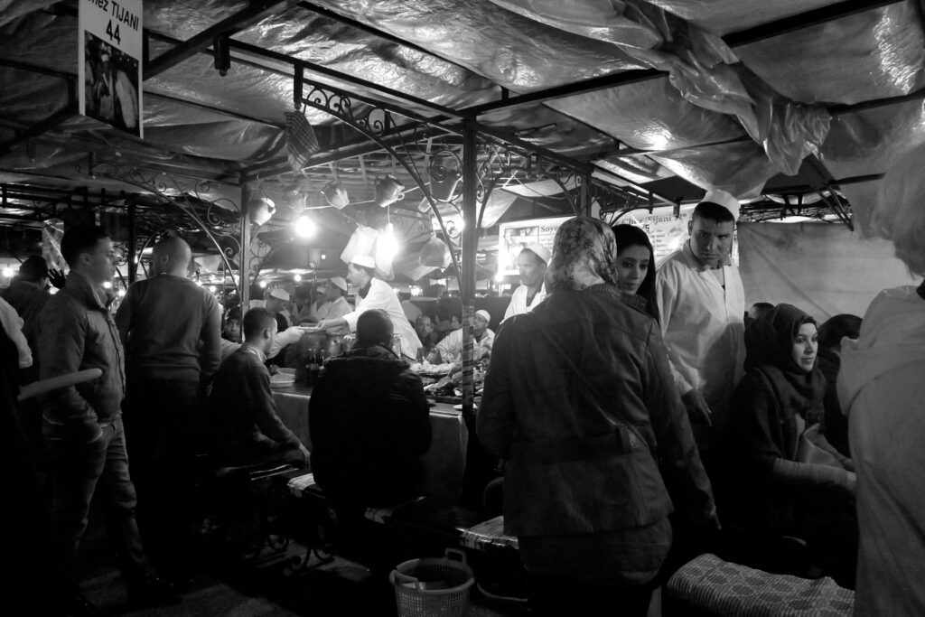 Cette photo en noir et blanc capture l'essence vibrante de la « cuisine populaire à Marrakech » dans le décor animé d'un marché.
