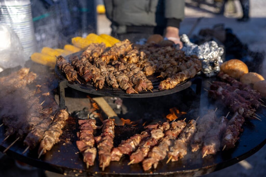 Cette image capture l'essence de la cuisine populaire à Marrakech avec une présentation vibrante de kebabs grésillants sur un gril rotatif.