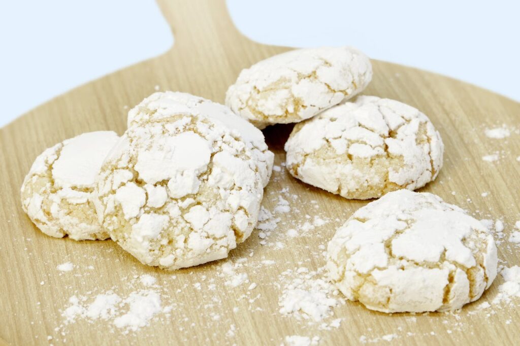Cette image présente une sélection alléchante de pâtisseries marocaines, issues des recettes marocaines comme la ghriba délicatement disposées sur une planche en bois.