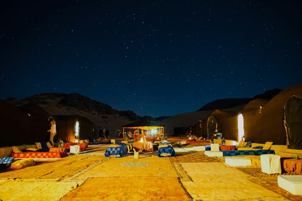Campement nocturne sous un ciel étoilé dans le désert marocain, avec des tentes traditionnelles. Une expérience d’Hébergement Authentique Maroc : Riads, Kasbahs & Bivouacs Écologiques