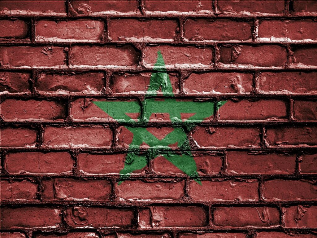 L'image présente un mur de briques rouges. Au centre, un dessin stylisé de l'étoile verte du drapeau marocain est peint. Cela évoque la comparaison Maroc ou Tunisie ?
