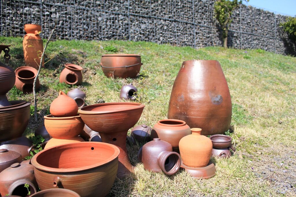 Une collection d'ustensiles en terre cuite artisanale, comprenant des pots, des jarres et des plats variés. Ces objets reflètent le savoir-faire traditionnel lié à la "cuisine marocaine authentique"