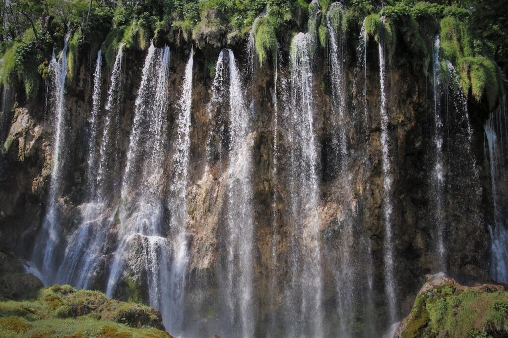 Une majestueuse cascade à plusieurs niveaux s’écoule sur une falaise verdoyante, dans les paysages du Maroc.