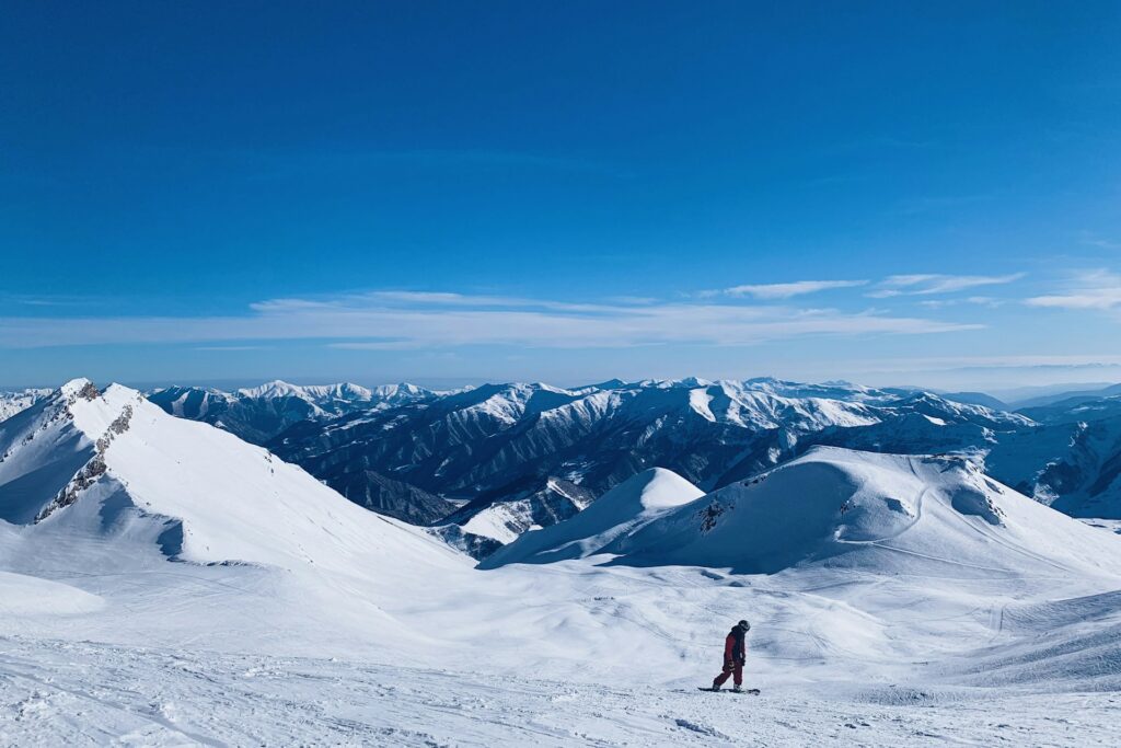 Panorama de montagnes enneigées sous un ciel bleu éclatant, révélant des escapades de neiges au Maroc.