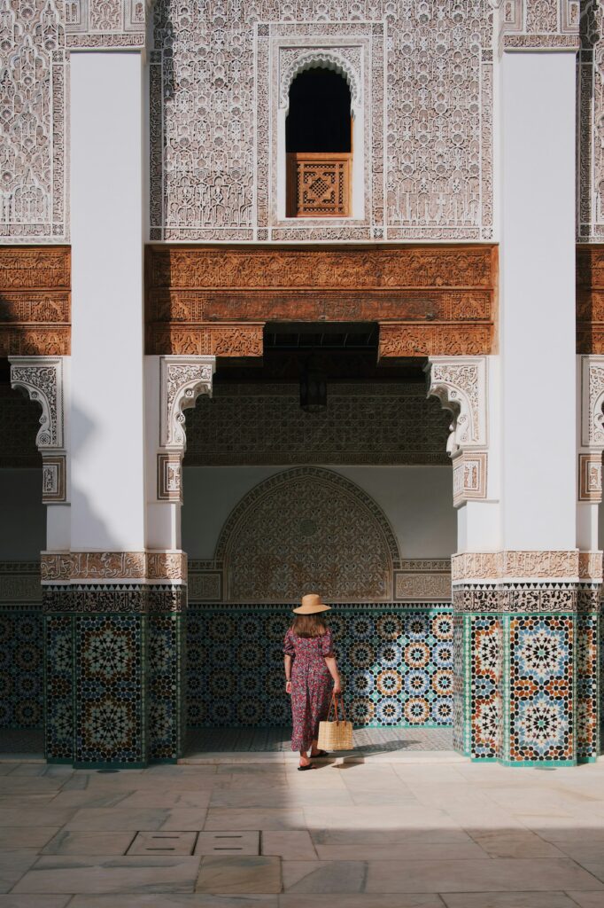 Femme vêtue d’une robe longue, marchant dans une cour traditionnelle Marocaine, en s’habillant dans le respect de la culture locale.