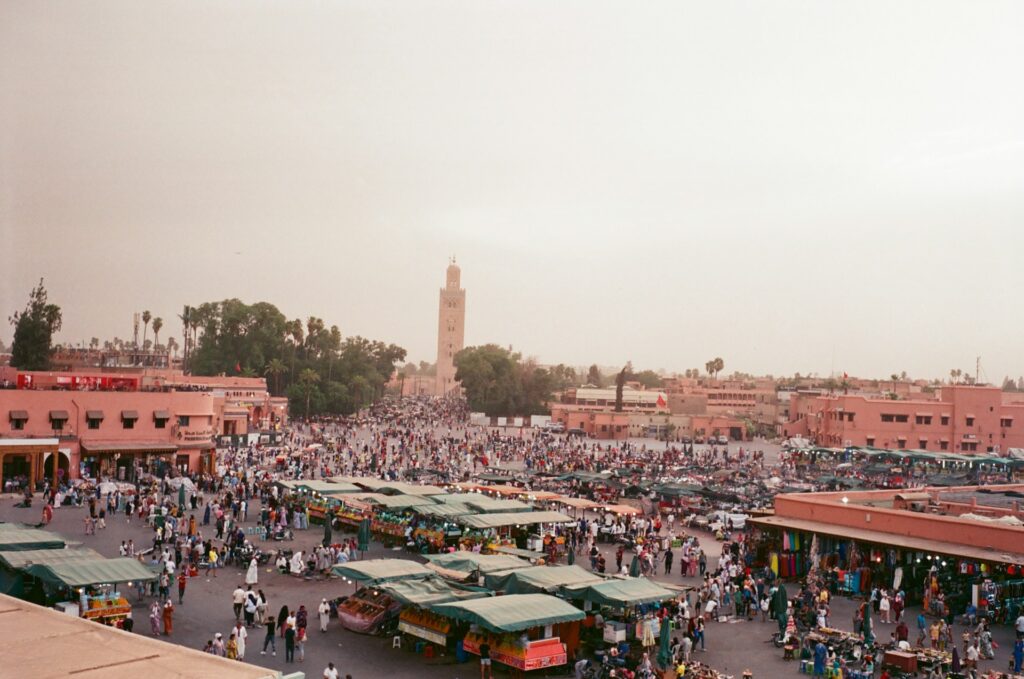 Vue panoramique animée de la place Jemaa el-Fna à Marrakech, avec ses stands, capturant l’ambiance vibrante des Vacances Maroc Fin d'Année 2025.