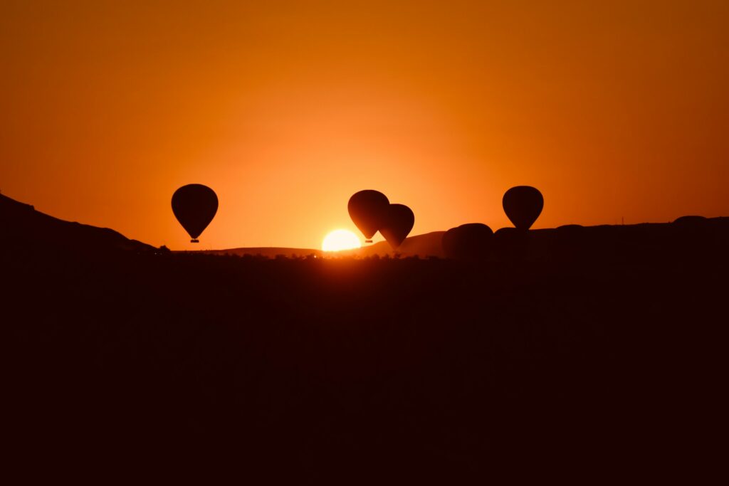 Une magnifique silhouette de plusieurs ballons en plein survol de Marrakech en montgolfière, s'élevant paisiblement face à un splendide coucher de soleil.