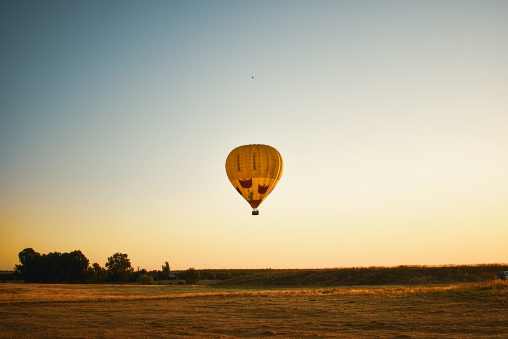 Un seul ballon jaune s'élève lors d'un paisible survol de Marrakech en montgolfière au-dessus d’une vaste plaine dorée.