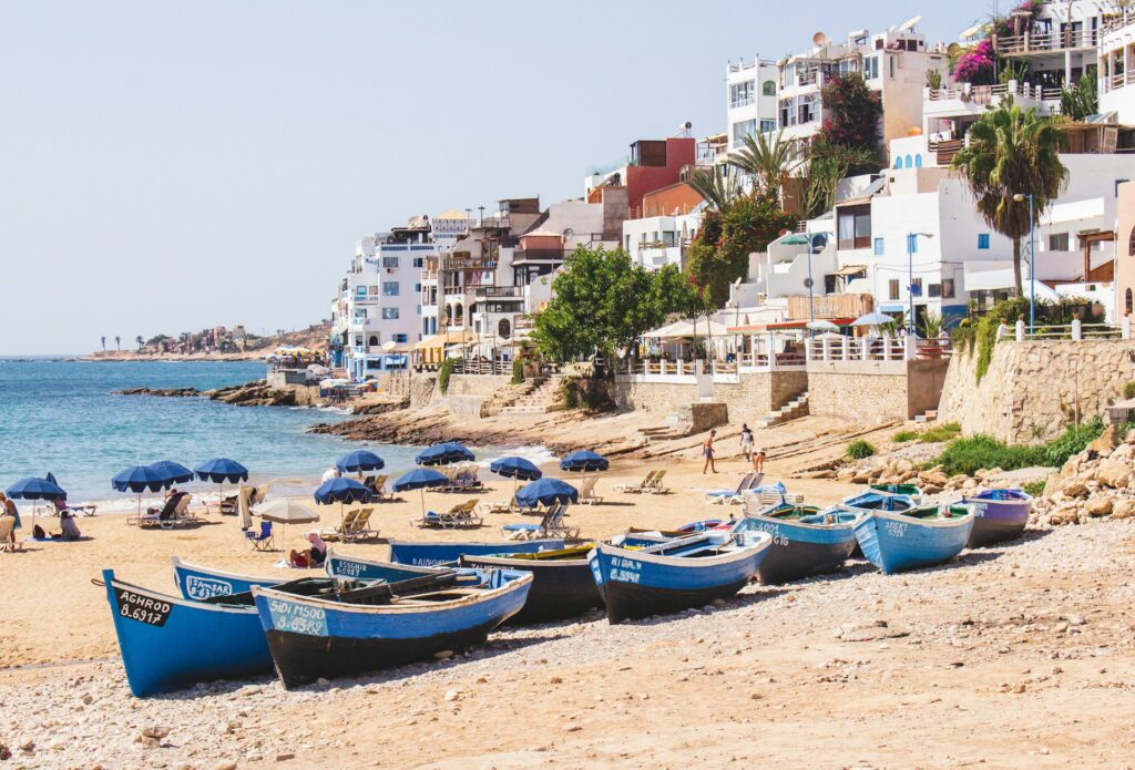 Vue de Taghazout près d’Agadir avec ses barques de pêche traditionnelles. Cette scène illustre parfaitement l’expérience « Visiter Agadir et ses environs«.