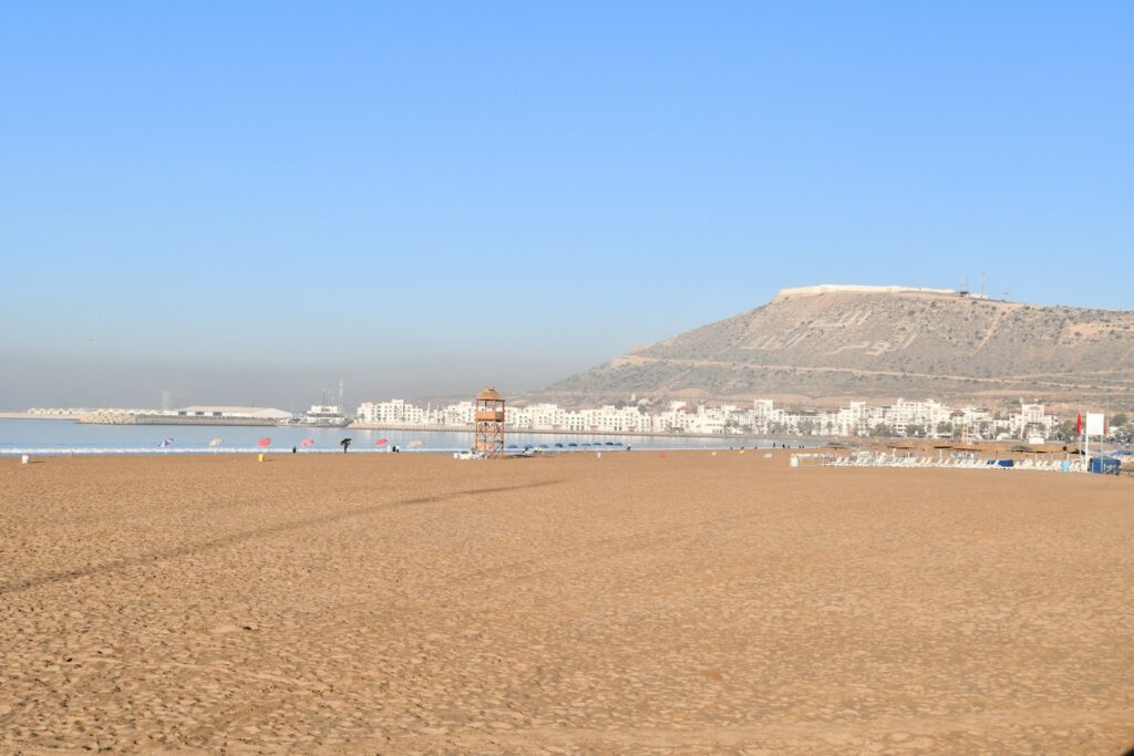 Vue panoramique de la plage d’Agadir avec son immense étendue de sable doré. Cette image illustre parfaitement l’expérience : Visiter Agadir et ses environs
