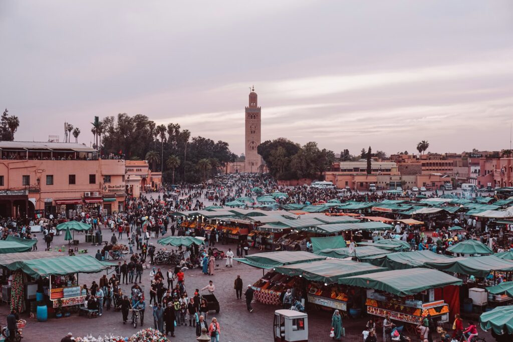 L’image illustre l’effervescence de la place Jemaa el-Fna à Marrakech, avec ses étals animés, sa foule dense. Elle évoque l’intensité de la médina et l`importance des Conseils pratiques avant de visiter Marrakech