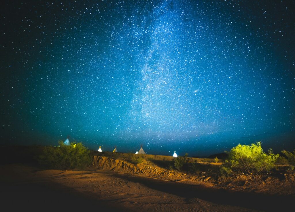 Sous un ciel nocturne d’un bleu intense, parsemé d’une multitude d’étoiles et traversé par la Voie lactée, un paysage désertique s’étend à perte de vue. Cette scène enchanteresse capture l’essence des Excursions dans le Sahara marocain, où l’on peut contempler la magie du désert sous un ciel étoilé d’une pureté exceptionnelle.