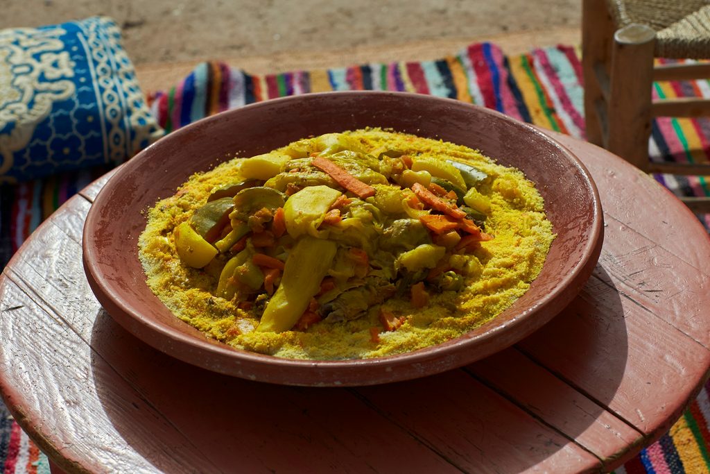 Couscous aux légumes colorés servi en plein air sur une table traditionnelle pendant une Visite gastronomique à Marrakech.